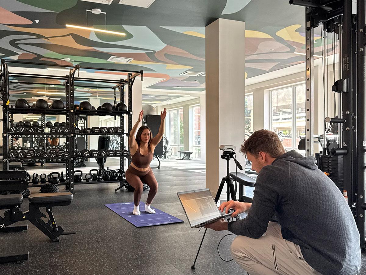 a woman exercises on a mat in a gym with colorful ceiling patterns