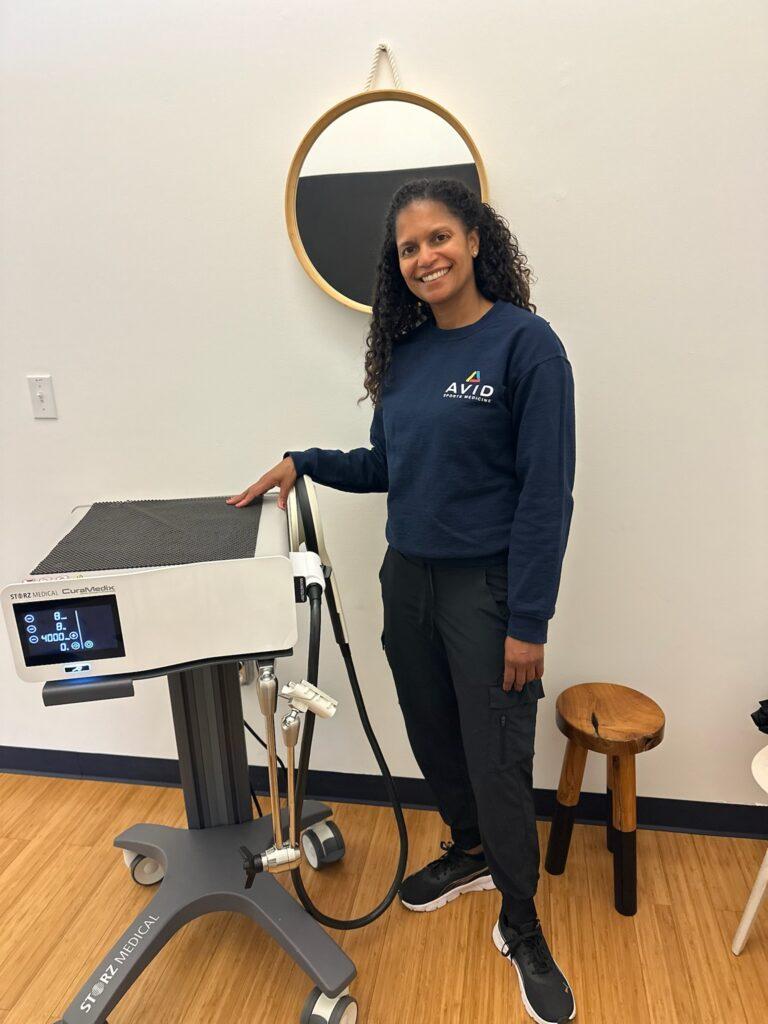 Dr. Veronica Jow standing next to Shockwave therapy equipment at Avid Sports Medicine